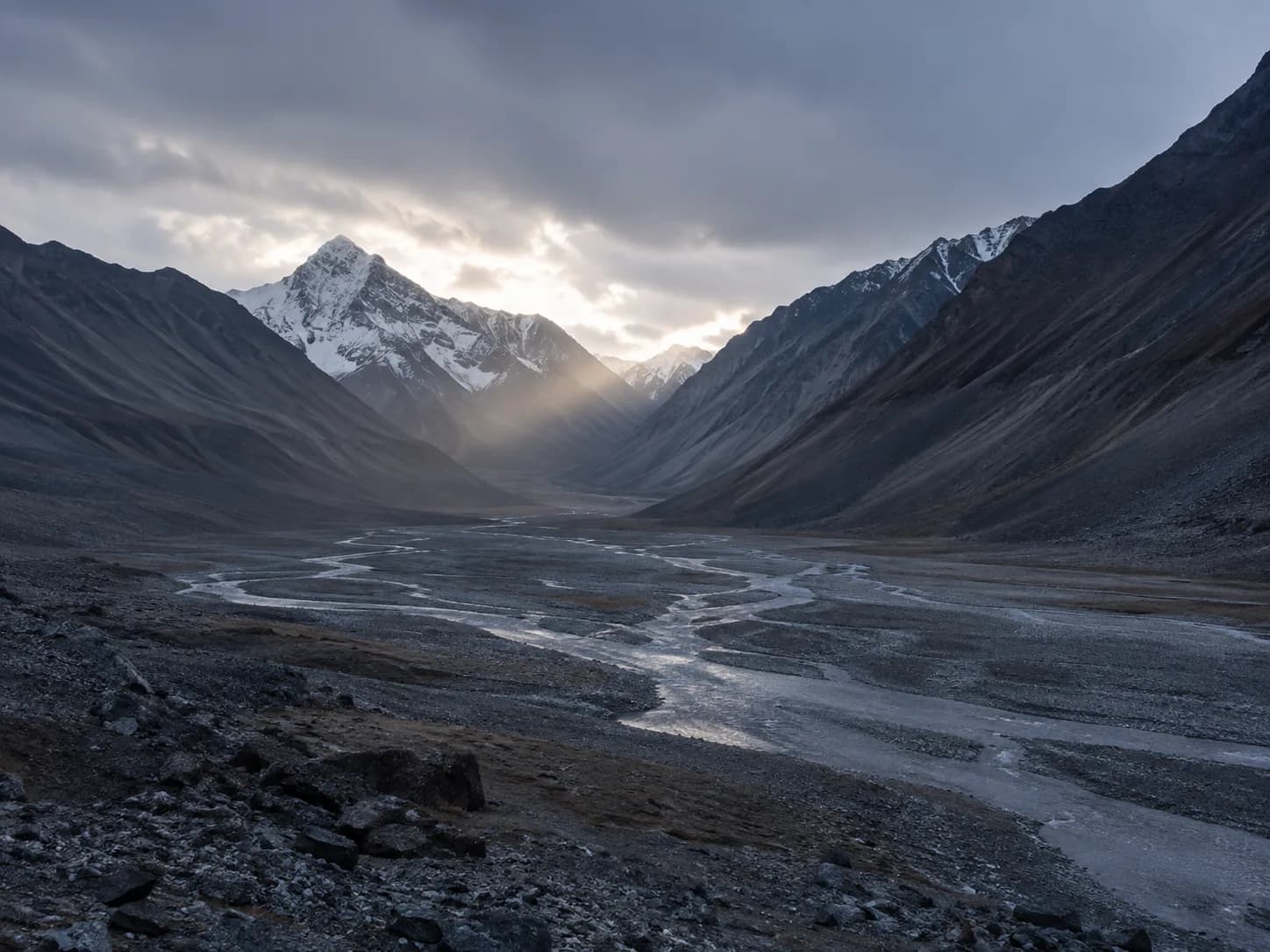 A thin road cut across a vast rock face above a shadowed valley